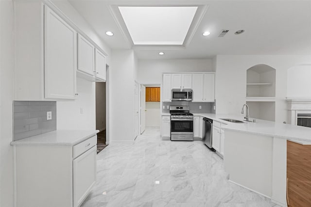 kitchen with appliances with stainless steel finishes, a sink, a peninsula, recessed lighting, and light countertops