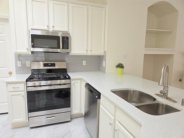 kitchen featuring appliances with stainless steel finishes, a sink, backsplash, and white cabinetry
