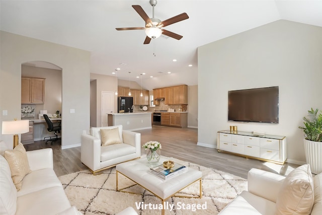 3954 Brangus Dr, Mckinney, TX 75071 - living room with arched walkways, light wood-style flooring, built in desk, vaulted ceiling, and ceiling fan