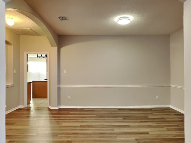 1114 Huntington Trl, Mansfield, TX 76063 - empty room with arched walkways, visible vents, a textured ceiling, and wood finished floors