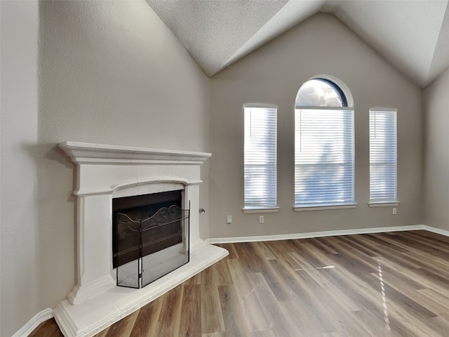 1114 Huntington Trl, Mansfield, TX 76063 - unfurnished living room featuring a fireplace with raised hearth, wood finished floors, and vaulted ceiling
