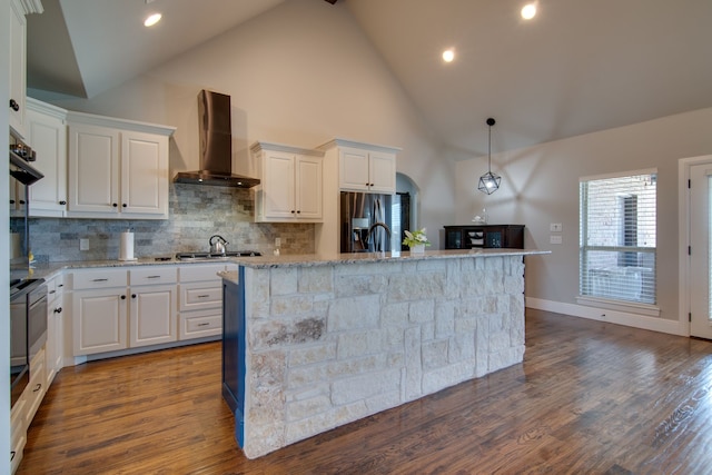 kitchen featuring appliances with stainless steel finishes, tasteful backsplash, wall chimney exhaust hood, and white cabinetry