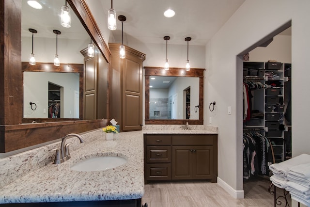 full bath featuring double vanity, a sink, baseboards, and a walk in closet