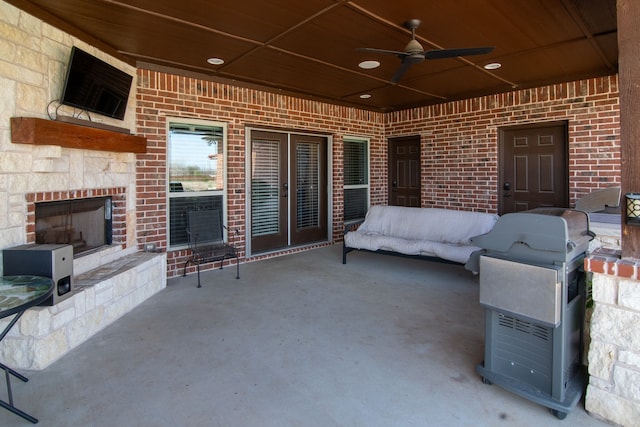 view of patio featuring ceiling fan, a large fireplace, and french doors