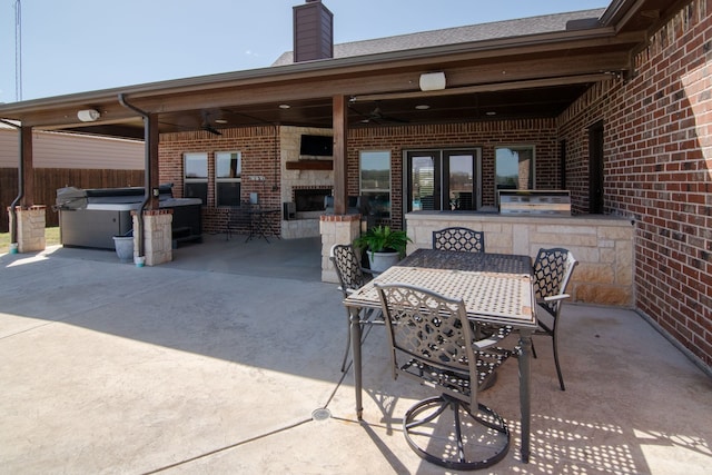 view of patio / terrace featuring a hot tub, an outdoor kitchen, a ceiling fan, and outdoor dining area