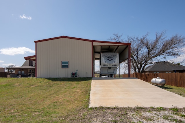 view of outbuilding with concrete driveway and fence