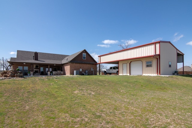 rear view of property with a detached garage, a lawn, central AC, and an outbuilding