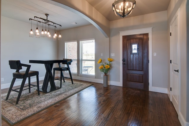 foyer entrance featuring arched walkways, baseboards, wood finished floors, and a chandelier