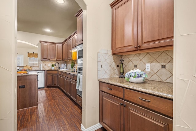 kitchen featuring decorative backsplash, stainless steel appliances, dark wood-style floors, arched walkways, and recessed lighting