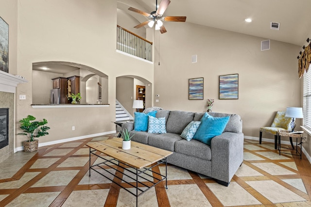 living room with arched walkways, baseboards, visible vents, a ceiling fan, and a towering ceiling