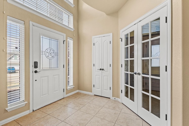 entryway featuring light tile patterned floors, baseboards, french doors, and plenty of natural light