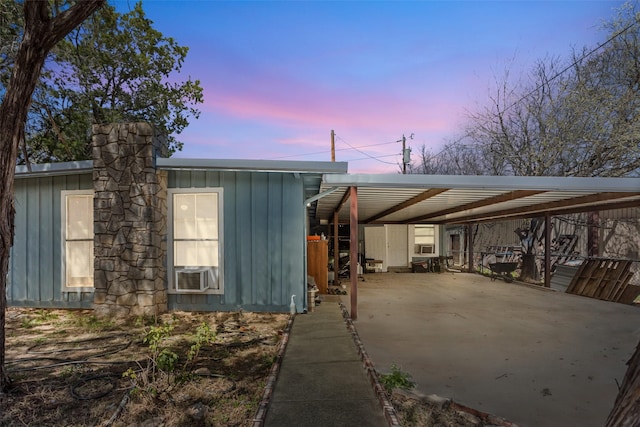 view of front of property featuring board and batten siding, a carport, cooling unit, and concrete driveway
