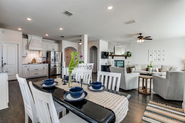 dining area with arched walkways, dark wood finished floors, visible vents, and ceiling fan
