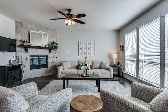living area with dark wood finished floors, a ceiling fan, and a tiled fireplace