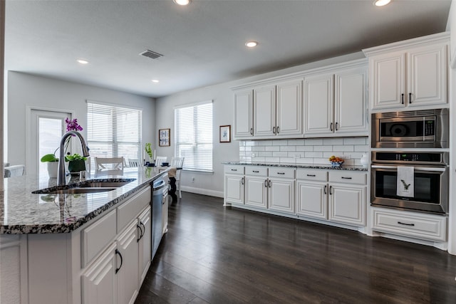 kitchen featuring stainless steel appliances, visible vents, stone countertops, a sink, and baseboards