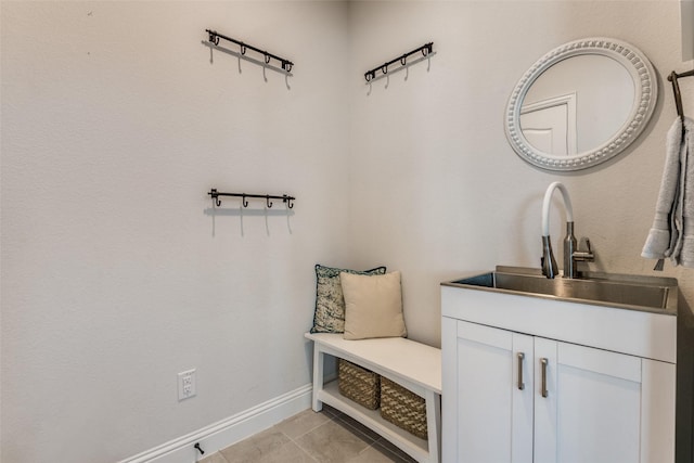 mudroom featuring baseboards, a sink, and light tile patterned flooring