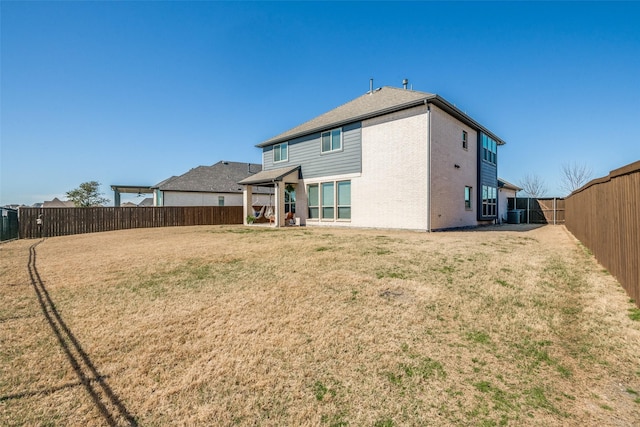 back of property with a lawn, a fenced backyard, and brick siding
