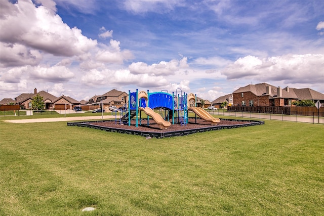 communal playground with fence, a yard, and a residential view