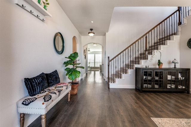 foyer entrance featuring wood finished floors, arched walkways, and stairway