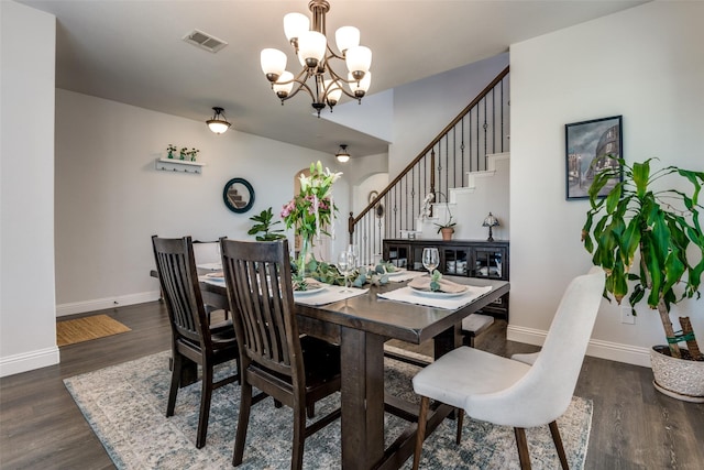 dining room featuring a chandelier, wood finished floors, visible vents, and baseboards