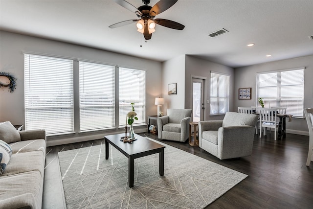 living room with a ceiling fan, baseboards, visible vents, and dark wood-style floors