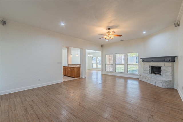 10471 Holly Creek Rd, Poetry, TX 75160 - unfurnished living room with light wood finished floors, a stone fireplace, ceiling fan with notable chandelier, and ornamental molding