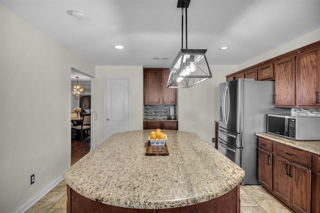 1607 Brandon St, Dallas, TX 75208 - kitchen featuring appliances with stainless steel finishes, a center island, backsplash, light stone counters, and decorative light fixtures