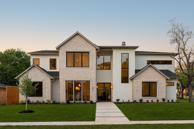 contemporary home with a front yard, brick siding, and stucco siding