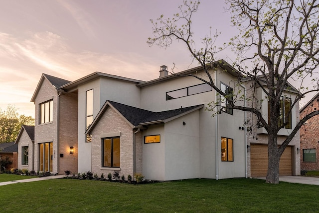 view of front of house featuring stucco siding, a yard, concrete driveway, and brick siding