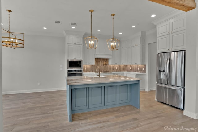 kitchen featuring tasteful backsplash, appliances with stainless steel finishes, a notable chandelier, white cabinets, and a sink