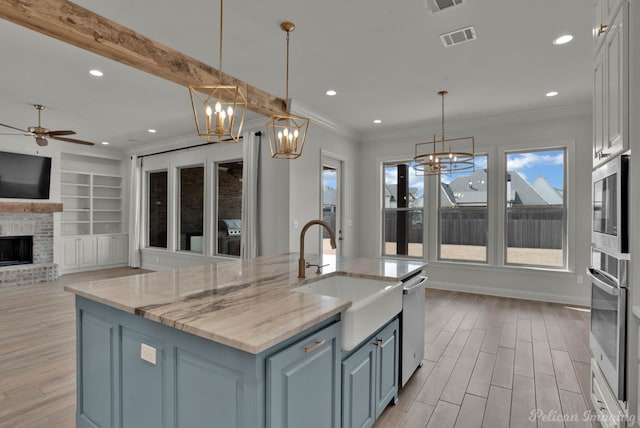 kitchen with visible vents, ornamental molding, a sink, stainless steel appliances, and light wood-style floors