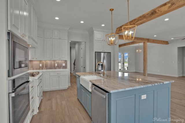 kitchen with tasteful backsplash, stainless steel appliances, a notable chandelier, white cabinetry, and a sink