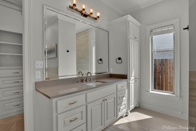bathroom with an inviting chandelier, vanity, crown molding, and baseboards
