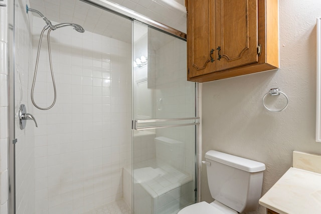 full bathroom featuring toilet, a stall shower, vanity, and a textured wall
