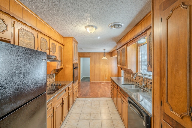 kitchen featuring brown cabinetry, visible vents, a sink, black appliances, and under cabinet range hood