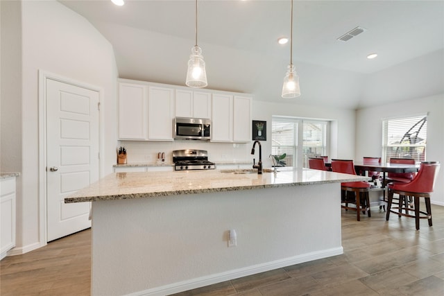kitchen featuring visible vents, a sink, white cabinetry, stainless steel appliances, and vaulted ceiling