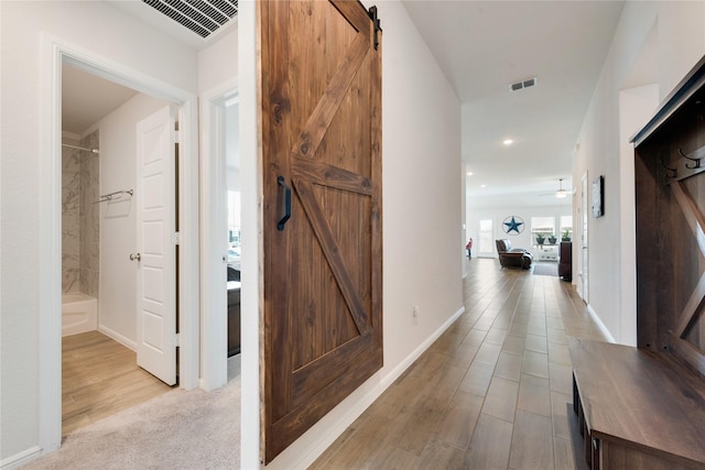 hall featuring visible vents, recessed lighting, baseboards, and a barn door