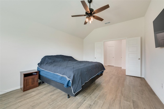 bedroom featuring light wood-type flooring, baseboards, visible vents, and vaulted ceiling