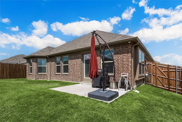 rear view of house featuring a patio, brick siding, a fenced backyard, and a lawn