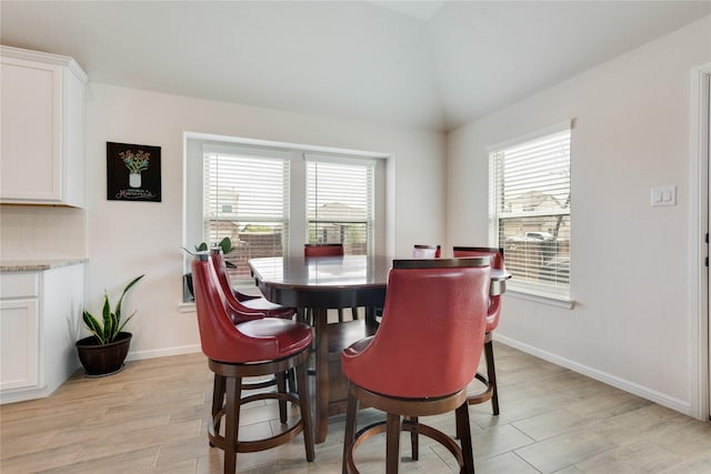 dining room featuring vaulted ceiling, plenty of natural light, and baseboards