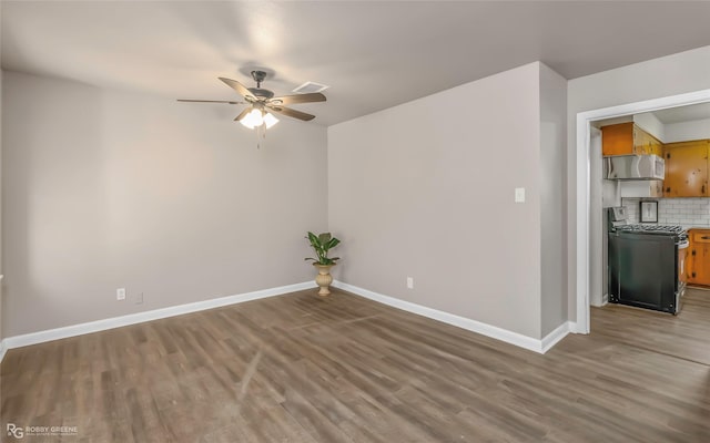 empty room with baseboards, wood finished floors, and a ceiling fan