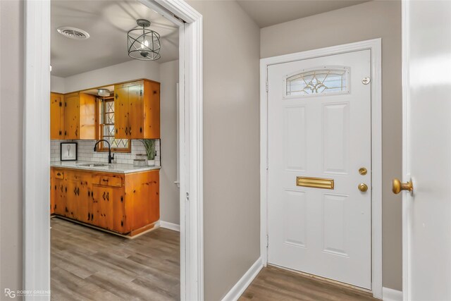 foyer entrance featuring visible vents, baseboards, and light wood-style flooring