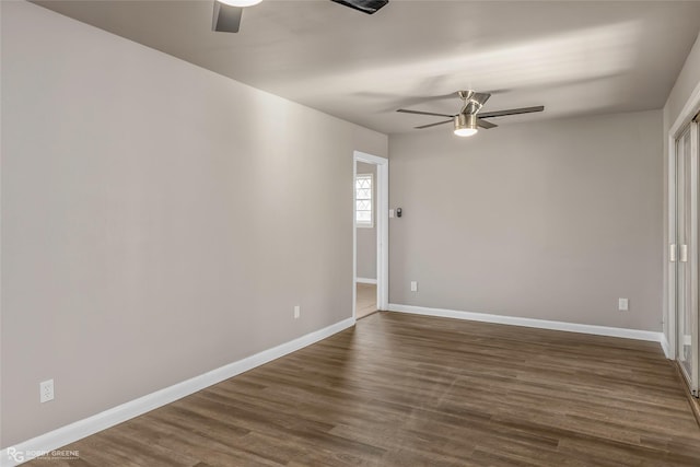 empty room featuring dark wood finished floors, baseboards, and ceiling fan