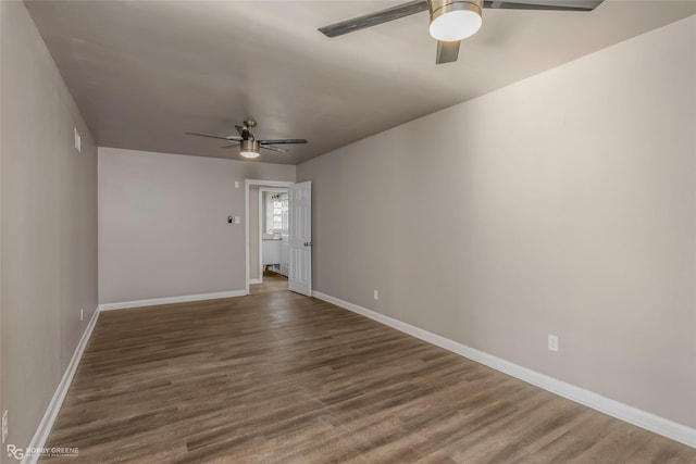 spare room with baseboards, dark wood-type flooring, and a ceiling fan
