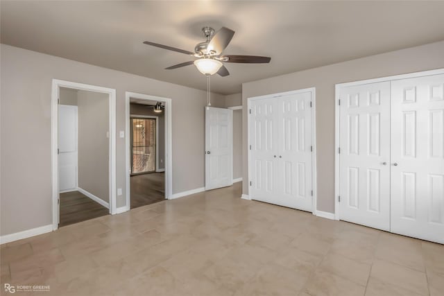 unfurnished bedroom featuring tile patterned floors, baseboards, multiple closets, and ceiling fan