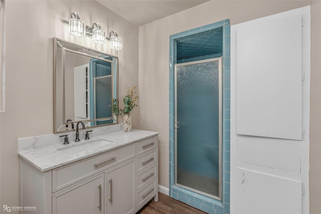 full bathroom with a stall shower, vanity, and wood finished floors