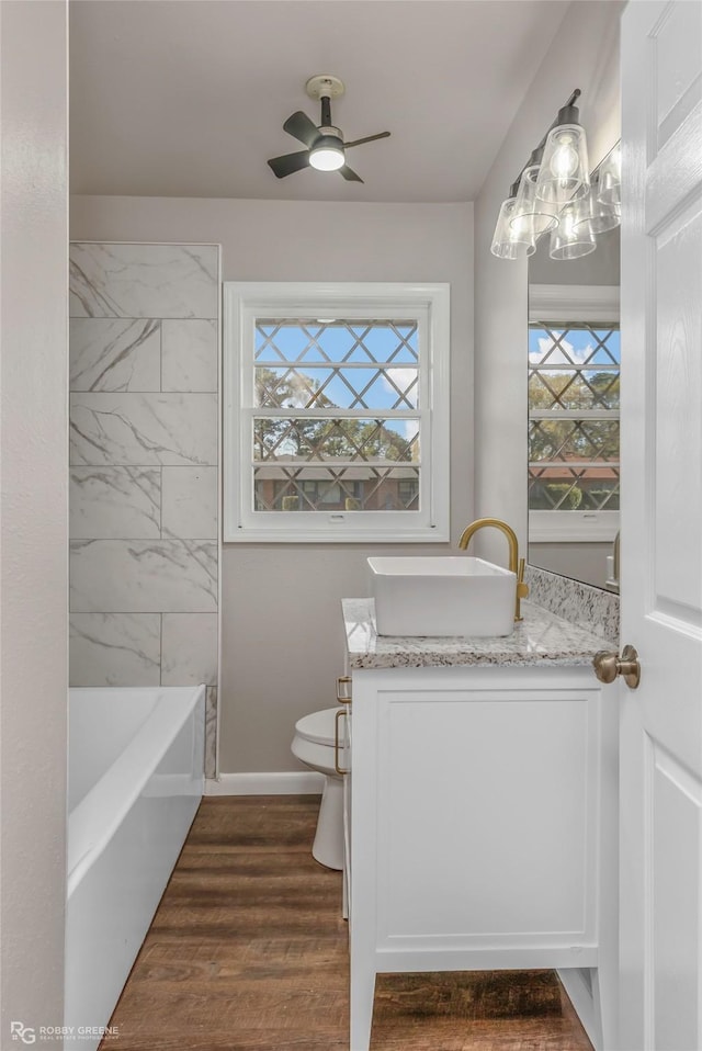 full bathroom featuring plenty of natural light, vanity, a ceiling fan, and wood finished floors