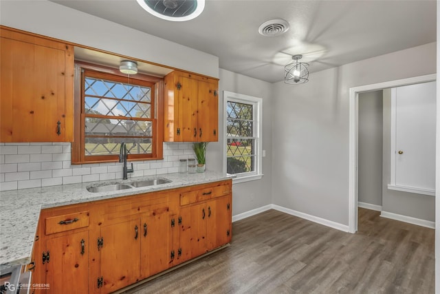 kitchen featuring visible vents, a sink, baseboards, decorative backsplash, and dark wood-style flooring