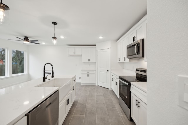 kitchen featuring appliances with stainless steel finishes, a sink, recessed lighting, white cabinetry, and hanging light fixtures