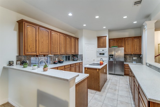 1500 Douglas Ave, Colleyville, TX 76034 - kitchen with stainless steel fridge, backsplash, a center island, recessed lighting, and brown cabinetry